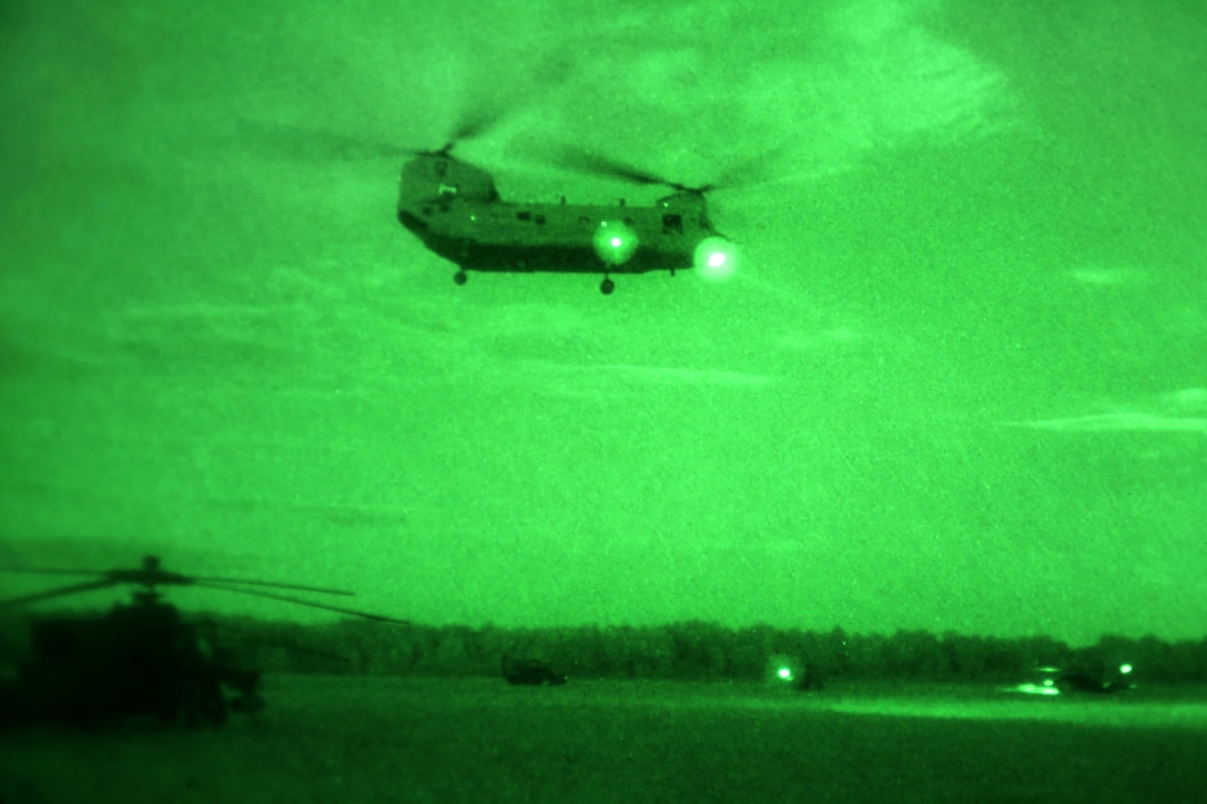 As seen through a night-vision device, a U.S. Army CH-47 Chinook helicopter flies over AH-64 Apache helicopters to conduct an air assault during NATO exercise Steadfast Javelin II on Lielvarde Airbase, Latvia, Sept. 7, 2014.