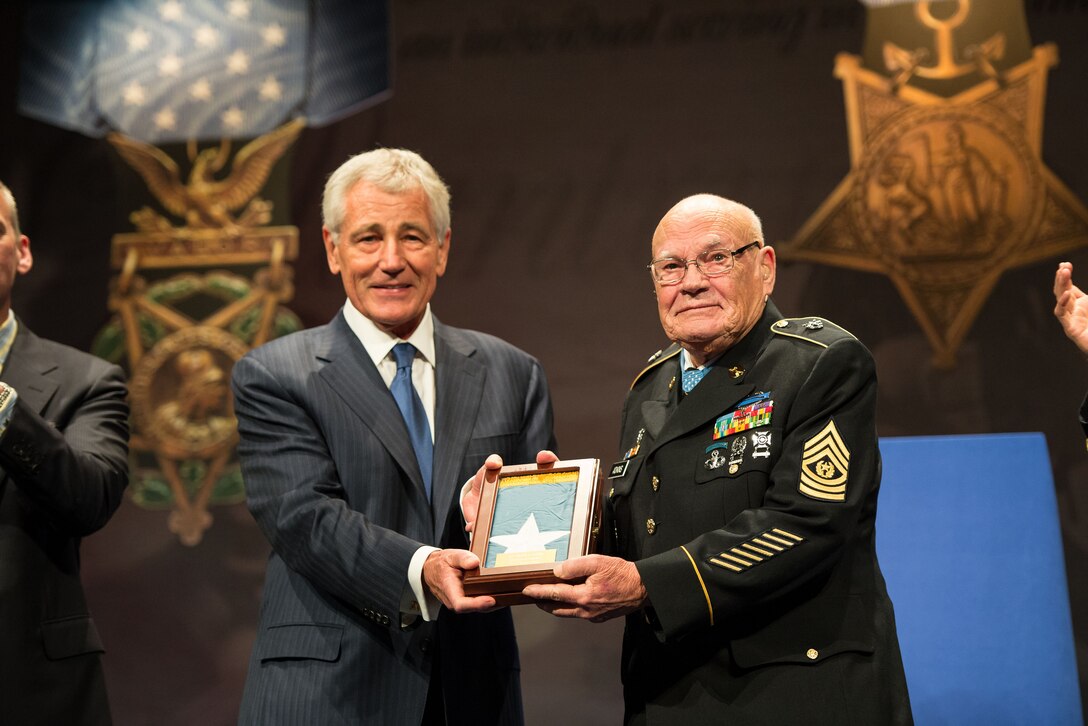 Defense Secretary Chuck Hagel, left, presents Medal of Honor recipient Army Command Sgt. Maj. Bennie G. Adkins with the Medal of Honor flag after inducting him into the Hall of Heroes during a ceremony at the Pentagon, Sept. 16, 2014. 