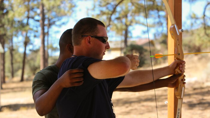 Lance Cpl. Carlos Morris, admin specialist, Headquarters Battalion, helps camper, Chase Neiberger learn how to shoot an archery bow at Camp Ronald McDonald in Mountain Center, Calif. on Sept. 13, 2014. Desert Arc has provided disabled adults with care and life skills for approximately 55 years.