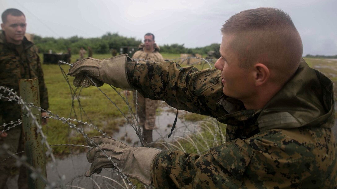 Lance Cpl. David Viboch, from Lake Stevens, Washington, a meteorological and oceanographic forecaster with Marine Air Control Squadron 4, Marine Air Control Group 18, 1st Marine Aircraft Wing, III Marine Expeditionary Force, sets up concertina wire around a compound in preparation of Valiant Shield 2014 at Tinian, North Marianas Islands.  Valiant Shield is a U.S.-only exercise integrating U.S. Navy, Air Force, Army and Marine Corps assets, offering real-world joint operational experience to develop capabilities that provide a full range of options to defend U.S. interests and those of its allies and partners. (U.S. Marine Corps photo by Lance Cpl. Tyler Ngiraswei/ Released)