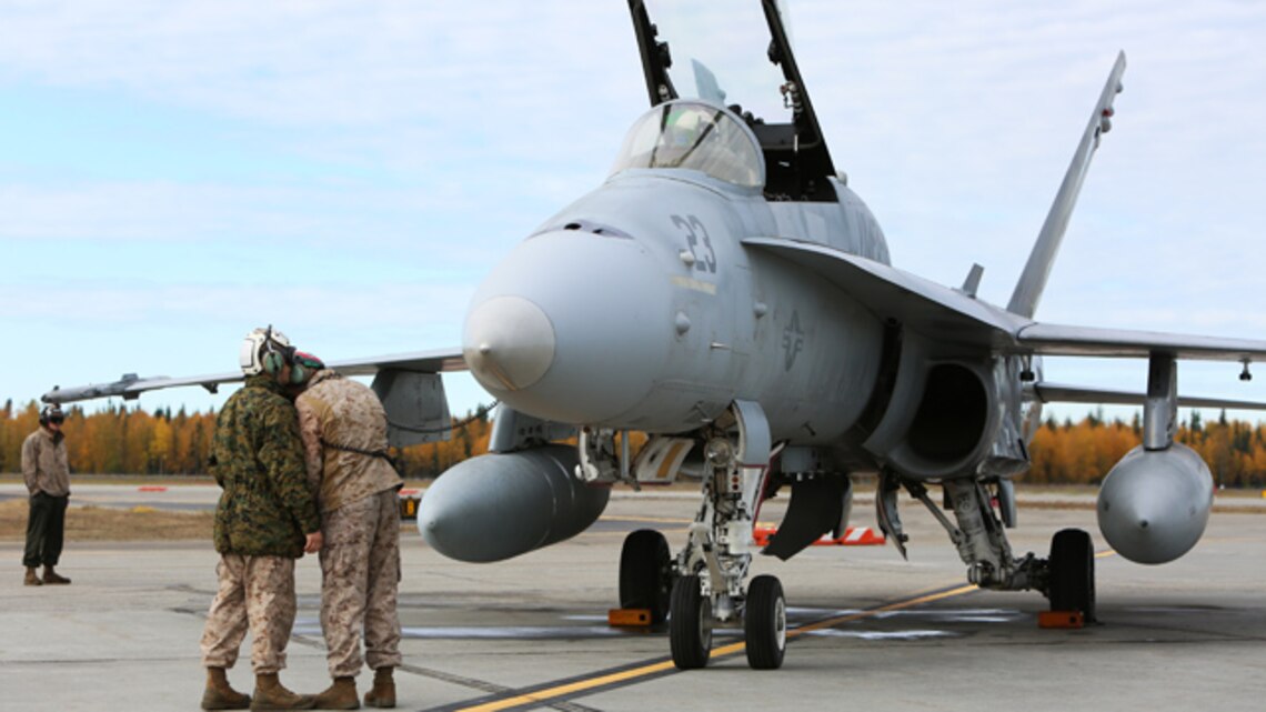 Sgt. Steven Johnson (wearing woodland gortex jacket), a quality assurance representative with Marine Fighter Attacks Squadron 122 and Fairbanks, Alaska native, assists a maintenance Marine with pre-flight turning of one of the squadron's F/A-18C Hornets, Sept. 11, 2014, aboard Eielson Air Force Base, Alaska. Marine Fighter Attack Squadron 122 is conducting unit level training in Alaska as part of Exercise Distant Frontier.