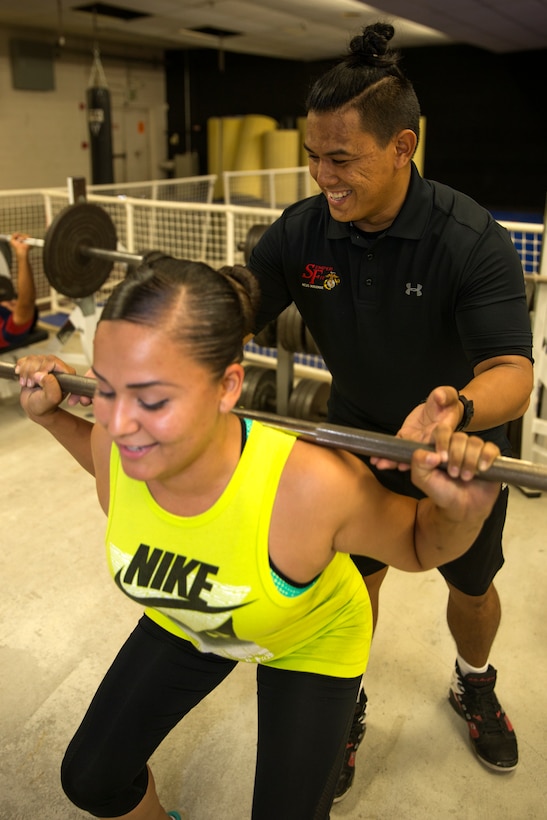 Randy Saldivar, a Return-to-Readiness program trainer, assists Lance Cpl. Leticia Sotelo, an aviation supply specialist with Marine Aviation Logistics Squadron (MALS) 11, with a squat during a lunch-time physical training session at the High Intensity Tactical Training Center aboard Marine Corps Air Station Miramar, Calif., Sept. 8. Saldivar worked his way through college as a personal trainer while earning a Bachelor’s Degree in Kinesiology, the study of movement in the human body.