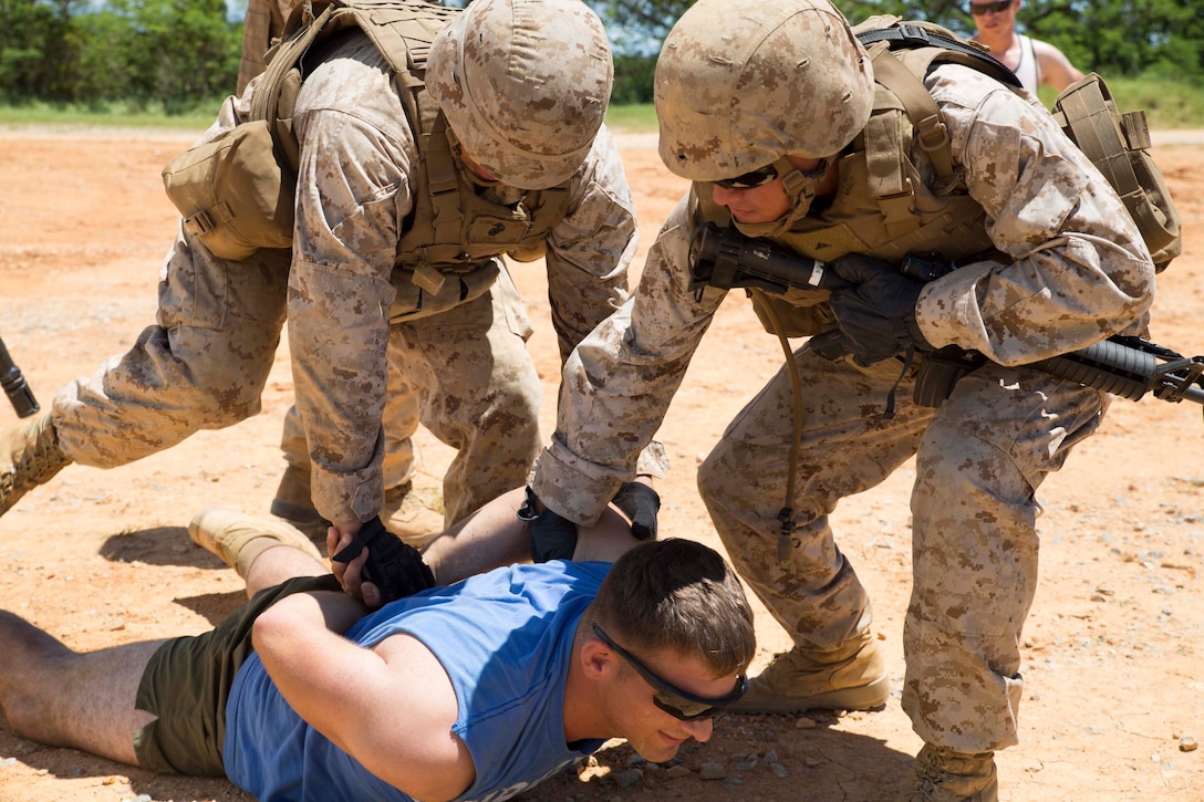 Lance Cpl. Tyler M. Culp, blue shirt, a Holt, Michigan, native, participates as a role player during noncombatant evacuation operations training Aug. 21 at the Central Training Area. Culp was an uncooperative evacuee during the scenario who was detained by Marines tasked with ensuring order was maintained. Culp is a bulk fuel specialist with Combat Logistics Battalion 4, 3rd Marine Logistics Group, III Marine Expeditionary Force. The detaining Marines are with Combat Logistics Regiment 3, 3rd MLG. (U.S. Marine Corps photo by Lance Cpl. Matt Myers/Released)
