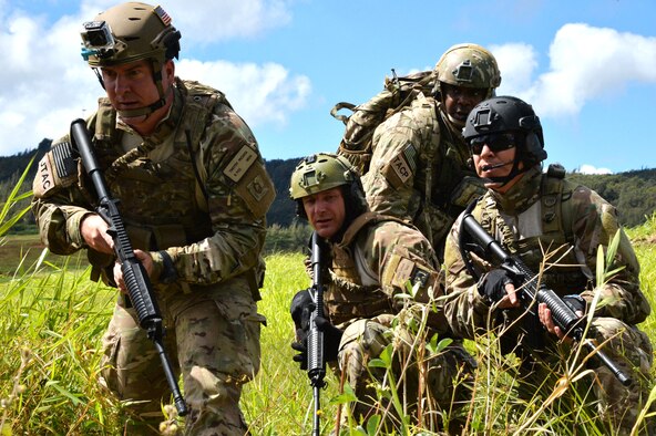 Air Force pararescue Airmen arrive at an evacuation point after parachuting into the area to make contact with downed aircrew members during a Wing Warrior Day training and exercise Sept. 12, 2014, at Kahuku Training Area on Oahu, Hawaii. The training was a refresher Survival, Evasion, Resistance and Escape course for the aircrew, and required them to evade enemy combatants, find and secure a safe area to stay overnight and establish communication with rescue units for an evacuation. Army and Marine aircraft and personnel also participated in the Warrior Day. (U.S. Air Force photo by Staff Sgt. Alexander Martinez)