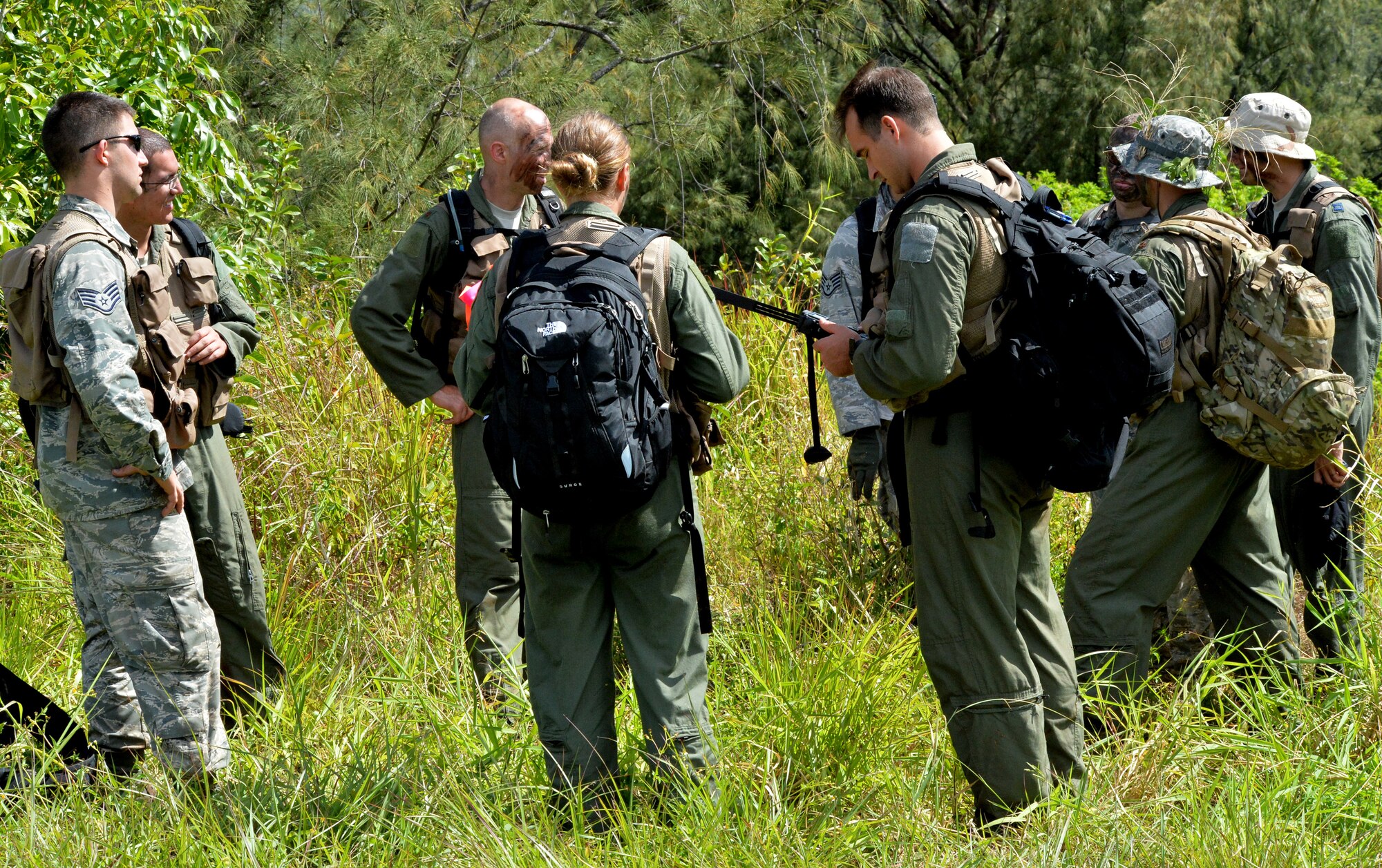 Aircrew members from the 535th Airlift Squadron, 65th AS and 96th Air Refueling Squadron gather at an evacuation point where they await contact with rescuers during a Wing Warrior Day training and exercise Sept. 12, 2014, at Kahuku Training Area on Oahu, Hawaii. The training was a refresher Survival, Evasion, Resistance and Escape course for the aircrew, and required them to evade enemy combatants, find and secure a safe area to stay overnight and establish communication with rescue units for an evacuation. Army and Marine aircraft and personnel also participated in the Warrior Day. (U.S. Air Force photo by Staff Sgt. Alexander Martinez) 