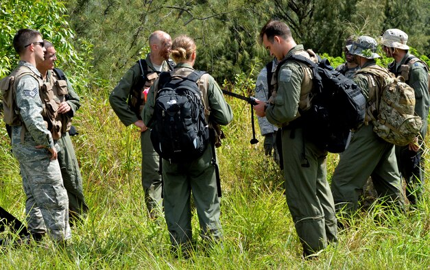 Aircrew members from the 535th Airlift Squadron, 65th AS and 96th Air Refueling Squadron gather at an evacuation point where they await contact with rescuers during a Wing Warrior Day training and exercise Sept. 12, 2014, at Kahuku Training Area on Oahu, Hawaii. The training was a refresher Survival, Evasion, Resistance and Escape course for the aircrew, and required them to evade enemy combatants, find and secure a safe area to stay overnight and establish communication with rescue units for an evacuation. Army and Marine aircraft and personnel also participated in the Warrior Day. (U.S. Air Force photo by Staff Sgt. Alexander Martinez) 