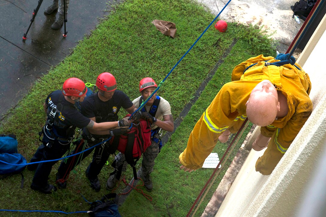 36th Civil Engineer Squadron firefighters hoist supplies to the roof of the Hot Spot to rescue a simulated victim during the Department of Defense Rescue Technician course culminating event Sept. 16th, 2014, on Andersen Air Force Base, Guam. Thirteen firefighters from Andersen, Naval Base Guam and the Guam Fire Department attended the three week course taught by 554th RED HORSE Squadron instructors.  (U.S. Air Force photo by Tech. Sgt. Zachary Wilson/Released)
