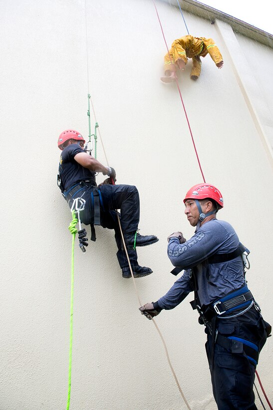 Firefighters assigned to Naval Base Guam ascend to the roof of the Hot Spot to rescue a simulated victim during the Department of Defense Rescue Technician course culminating event Sept. 16th, 2014, on Andersen Air Force Base, Guam. The specialized rescue course focused on elevated and confined space rescues was taught to a mix of U.S. Navy, Andersen and Guam firefighters by 554th RED HORSE firefighter instructors assigned to Silver Flag on Northwest Field. (U.S. Air Force photo by Tech. Sgt. Zachary Wilson/Released)