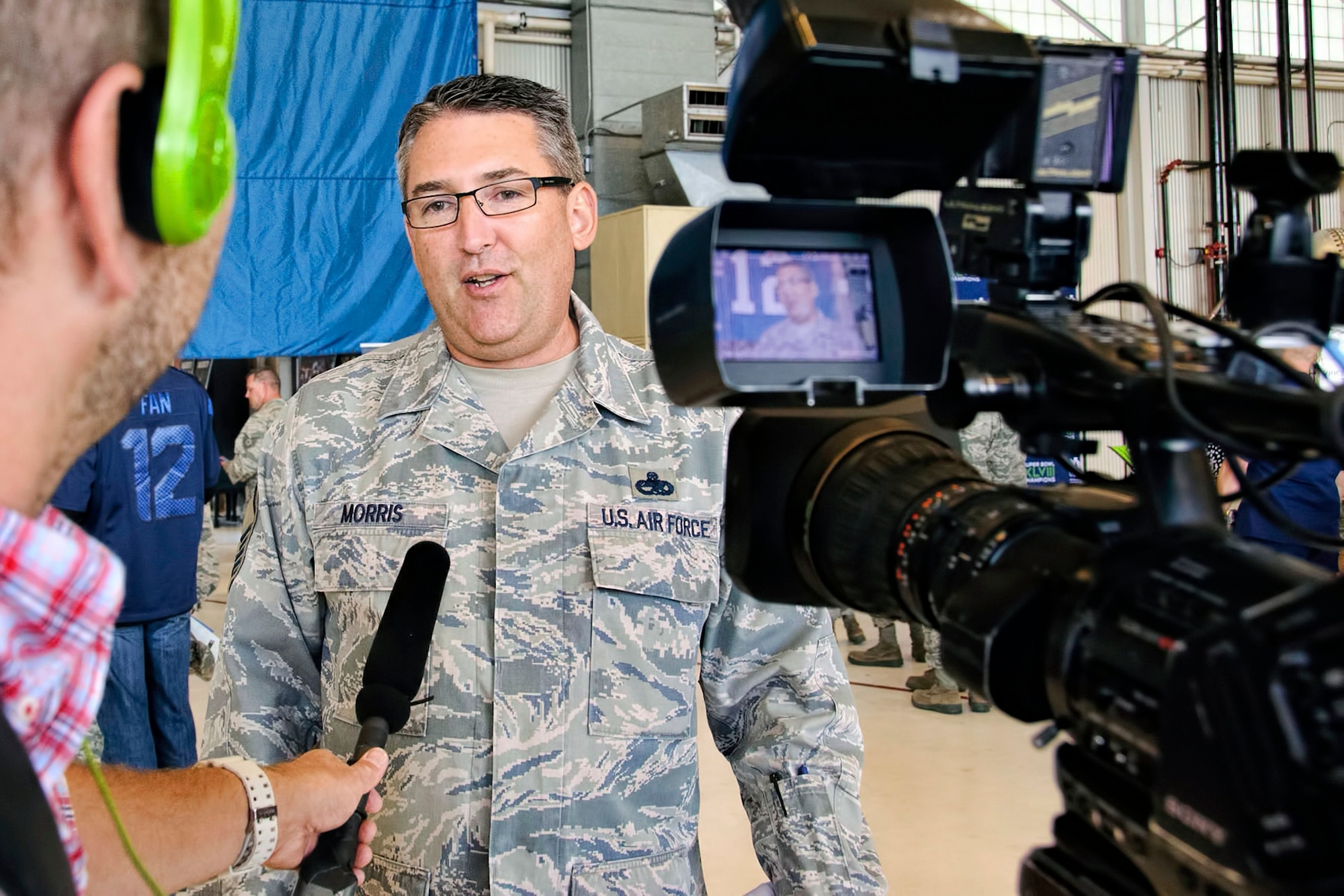 Chief Master Sgt. Daniel Morris, 446th Maintenance Group, is interviewed by a local news station covering the Seattle Seahawks military unit "change of command." The 446th Airlift Wing handed over the reins as the championship football team's military unit for the season to the Coast Guard District 13 Seattle, Sept. 9 at McChord Field, Washington. (U.S. Air Force Reserve photo by Jake Chappelle)