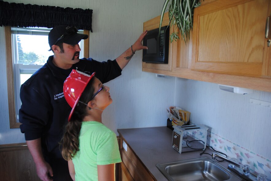 Air Force civilian fireman Justin Haskamp asks a young guest to identify as many fire hazards inside the small kitchen of the Kids Fire Safety House during the Grand Cities Community Celebration, Sept. 15, 2014, on the grounds of the Cliff Fido Purpur Arena in downtown Grand Forks, North Dakota. The Kids Fire Safety House is used by the Grand Forks Air Force Base Fire Department to teach children fire prevention skills by hunting for home fire hazards and practicing fire escape drills. (U.S. Air Force photo/Staff Sgt. Luis Loza Gutierrez) 

