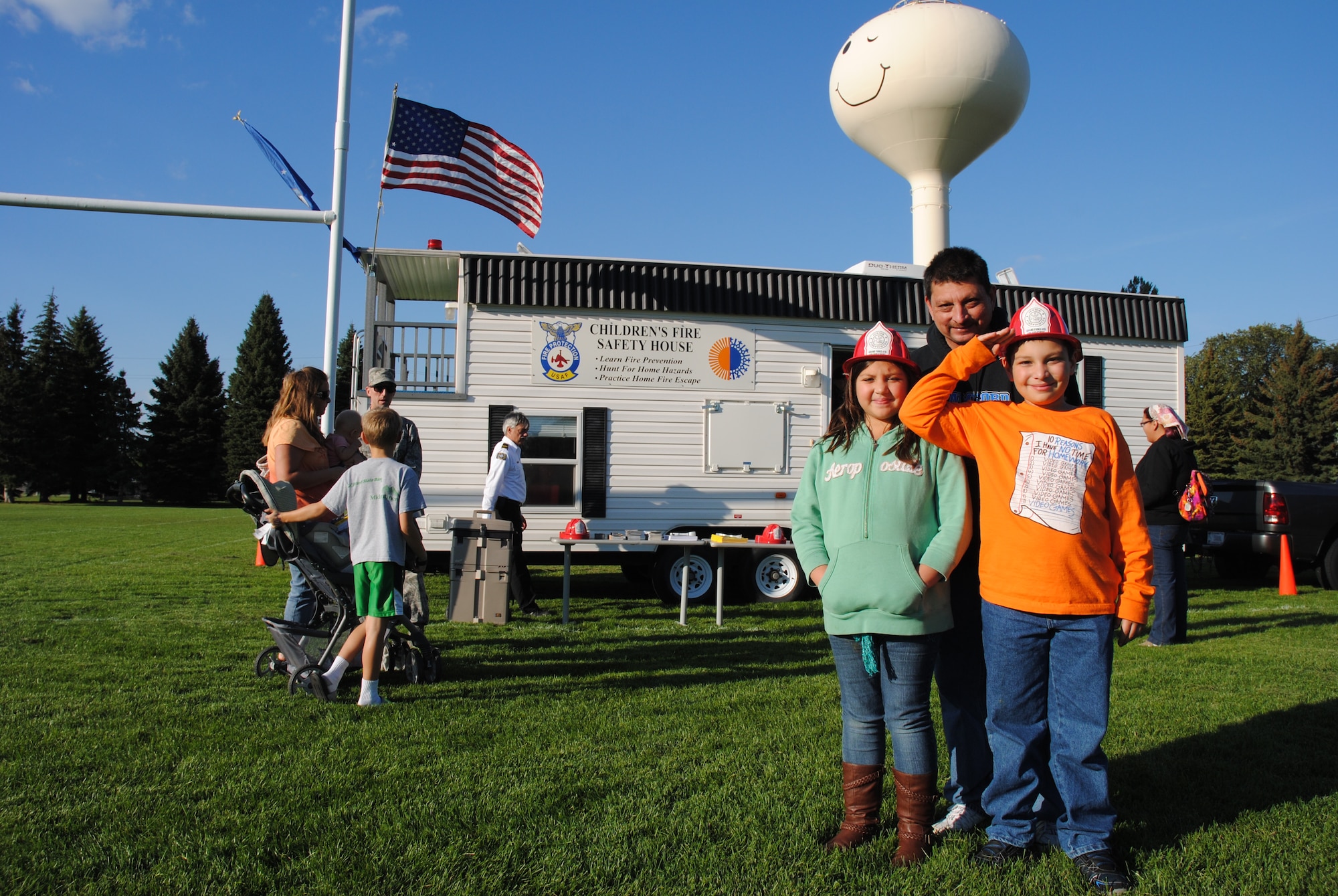 Grand Forks, N.D., resident Matthew Vasquez salutes a service member while posing for a photo with his father, David, and sister, Macy, after visiting the display put on by members of the Grand Forks Air Force Base Fire Department during the Grand Cities Community Celebration, Sept. 15, 2014 ,on the grounds of the Cliff Fido Purpur Arena in downtown Grand Forks. Residents such as the Vasquez family enjoyed meeting with the Warriors of the North.  (U.S. Air Force photo/Staff Sgt. Luis Loza Gutierrez) 

