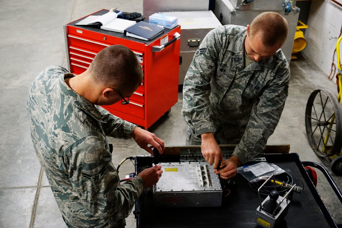 Airman 1st Class Thomas Berthiaume and Senior Airman Aarron Hey, 90th Maintenance Operations Squadron Power, Refrigeration and Electrical, conduct maintenance practice on a missile lauch facility workcage maintenance stand on F.E. Warren Air Force Base, Sept. 11, 2014. Berthiaume and Hey practiced in preparation for their competition during the Air Force Global Strike Challenge. (U.S. Air Force photo by Lan Kim)