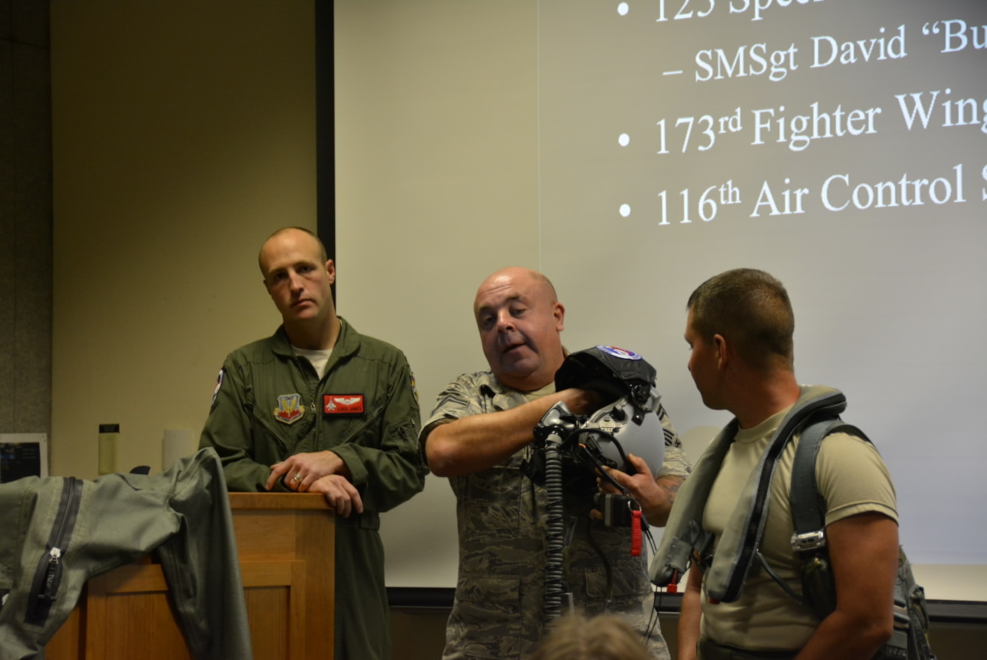 Members of the Oregon Air National Guard present a 142nd Fighter wing mission briefing and demonstrate life support equipment to the members of the visiting 381st Bomb Group (H) Memorial Association at Portland Air National Guard Base on Sept. 4, 2014.  Left to right are Capt. Robert Jones, Senior Master Sgt. David West and Tech. Sgt. Nathan Ruddell.  (Courtesy Dr. Kevin Wilson, 381BGMA Secretary-Treasurer/Historian)