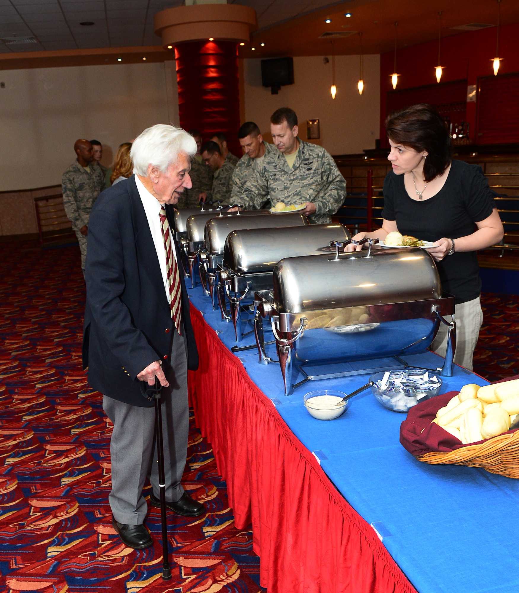 Sal Davidson, right, 100th Air Refueling Wing community relations advisor from Norwich, Norfolk, serves Harry Buckledee, left, former World War II prisoner of war from Sudbury, Suffolk, food during the Prisoner of War/Missing in Action Fallen Comrades Committee luncheon Sept. 17, 2014, at the Galaxy Club on RAF Mildenhall, England. Buckledee attended the luncheon to share his POW story with Team Mildenhall members. (U.S. Air Force photo/Airman 1st Class Jonathan Light/Released)