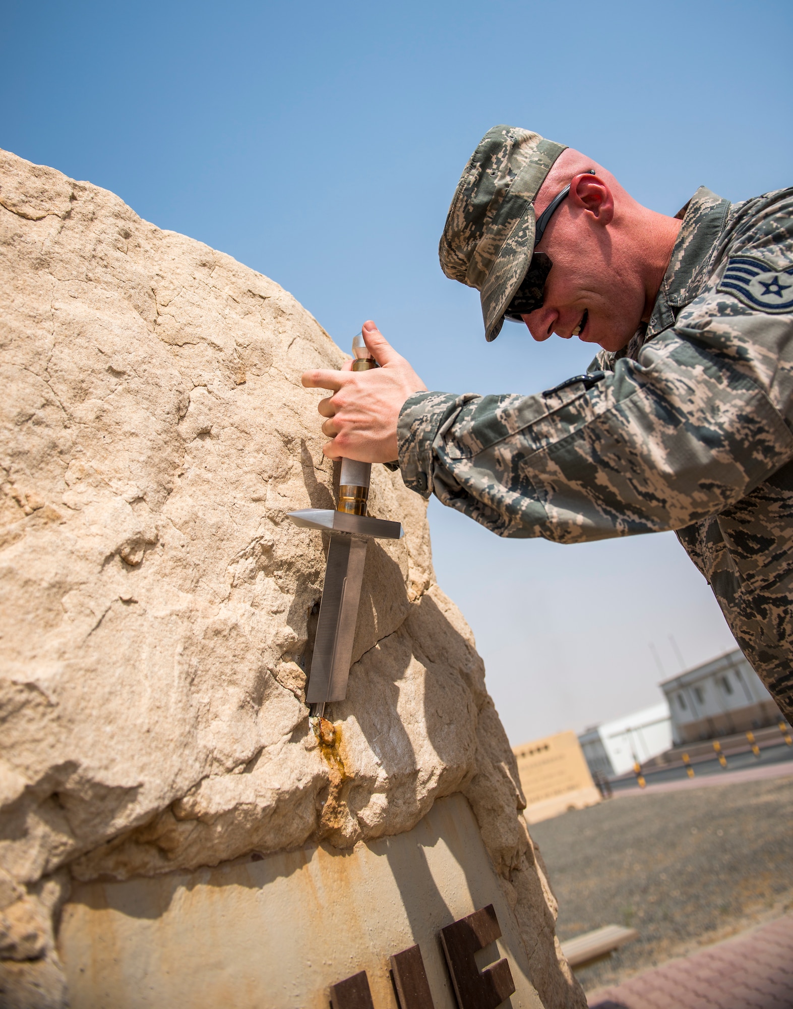 U.S. Air Force Staff Sgt. Justin Costanzo, 386th Expeditionary Maintenance Squadron aircraft maintenance technician, places the sword he helped craft inside The Rock Aug. 19, 2014 at an undisclosed location in Southwest Asia. Costanzo, along with Staff Sgt. Jarrod McMillian, spent over 140 man-hours designing and building the sword. Costanzo deployed from Shaw Air Force Base, S.C. in support of Operation Enduring Freedom. (U.S. Air Force photo by Staff Sgt. Jeremy Bowcock)