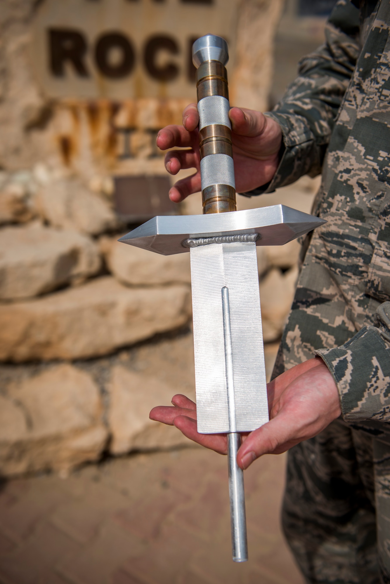 U.S. Air Force Staff Sgt. Justin Costanzo, 386th Expeditionary Maintenance Squadron aircraft maintenance technician, shows off the sword before placing it in The Rock Aug. 19, 2014 at an undisclosed location in Southwest Asia. Costanzo, along with Staff Sgt. Jarrod McMillian, spent over 140 man-hours designing and building the sword. Costanzo deployed from Shaw Air Force Base, S.C. in support of Operation Enduring Freedom.  (U.S. Air Force photo by Staff Sgt. Jeremy Bowcock)