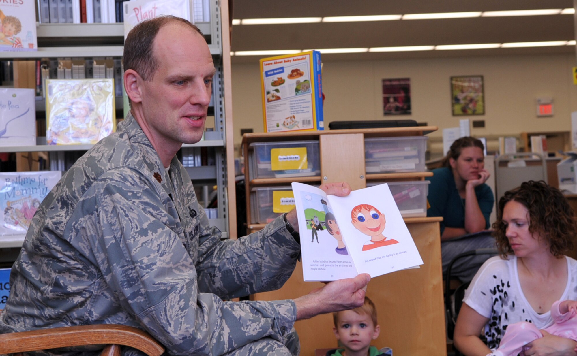 Maj. Thomas Oziemblowsky, 319th Force Support Squadron commander, reads "My Daddy is an Airman" to children at the library Sept. 17, 2014, on Grand Forks Air Force Base, N.D. The library holds weekly book readings and recently began inviting Airmen to lead a book reading once a month. (U.S. Air Force photo/Airman 1st Class Bonnie Grantham)