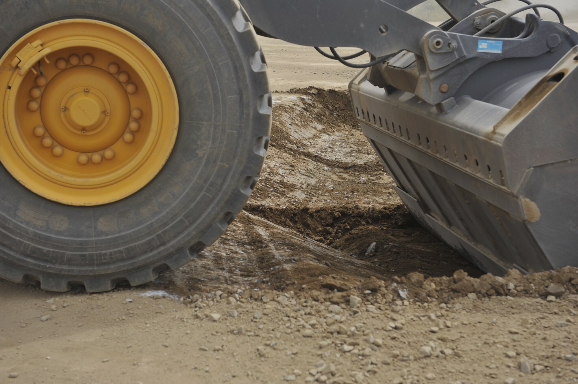 Senior Airman Kevin Bittinger, 51st Civil Engineer Squadron pavement and equipment journeyman, moves dirt to have an even layer of material in the crater on a flight line training site during a simulated crater repair for operational readiness exercise Beverly Midnight 14-4 Sept. 18, 2014, at Osan Air Base, Republic of Korea. This training provides the Airmen an opportunity to practice and hone their wartime capabilities. (U.S. Air Force photo by Senior Airman David Owsianka)