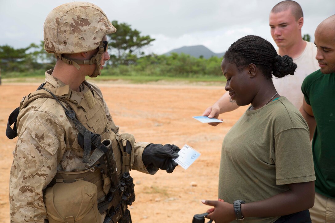 Lance Cpl. Devon M. Huffley, left, a York, Pennsylvania, native, takes fake passports from role players during noncombatant evacuation operations training Aug. 21 at the Central Training Area. The role players going through the screening point simulated they were from different countries and spoke multiple languages in order to increase the realism of the scenario. Huffley is a motor vehicle operator with Combat Logistics Regiment 3, 3rd Marine Logistics Group, III Marine Expeditionary Force. The role players are Marines with Combat Logistics Battalion 4, 3rd MLG. (U.S. Marine Corps photo by Lance Cpl. Matt Myers/Released)