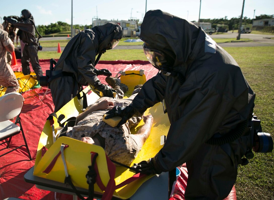 Chemical, biological, radiological and nuclear defense specialist Marines scrub down a simulated casualty during an assessment and consequence management response training event Aug. 27 at Marine Corps Air Station Futenma. The training event involved responding to calls regarding hazardous material. The Marines are with Marine Wing Headquarters Squadron 1, 1st Marine Aircraft Wing, III Marine Expeditionary Force. (U.S. Marine Corps photo by Lance Cpl. Tyler Ngiraswei/Released)