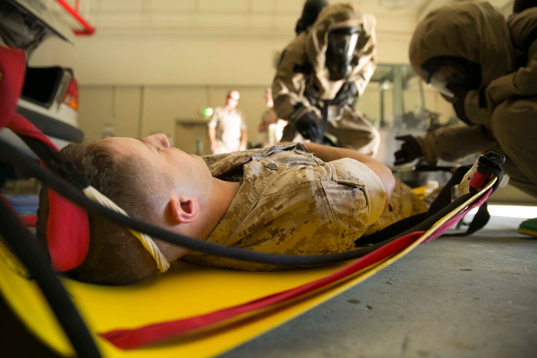 Marines pull a simulated casualty, suspected of exposure to hazardous material, onto a stretcher during an assessment and consequence management response training event Aug. 27 at Marine Corps Air Station Futenma. The casualties were brought to a decontamination table where they were cut out of their clothes, cleaned and then transported to a medical facility. The Marines are chemical, biological, radiological and nuclear defense specialists with Marine Wing Headquarters Squadron 1, 1st Marine Aircraft Wing, III Marine Expeditionary Force. (U.S. Marine Corps photo by Lance Cpl. Tyler Ngiraswei/Released)
