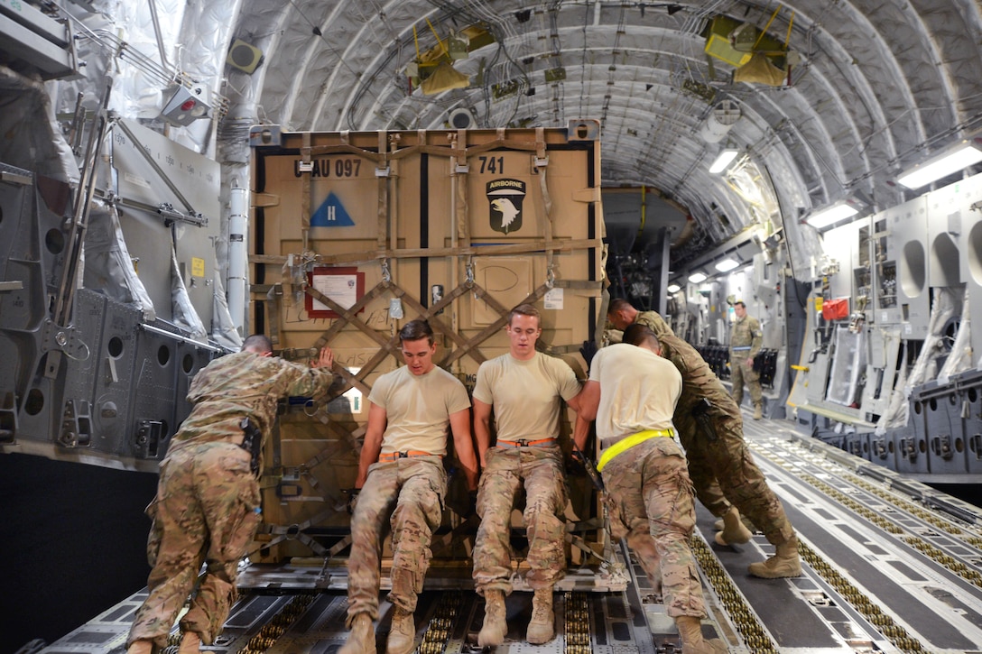 U.S. soldiers and airmen load a container full of supplies for an AF-64 Apache helicopter onto a C-17 Globemaster III on Bagram Airfield, Afghanistan, Sept. 9, 2014.