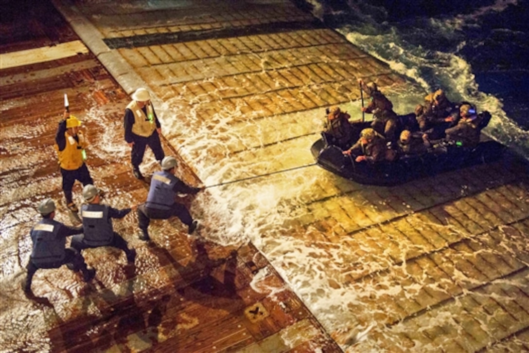 U.S. Navy sailors pull a combat rubber raiding craft carrying Marines into the well deck of the amphibious dock landing ship USS Germantown during amphibious operations in the Philippine Sea, Sept. 11, 2014. 