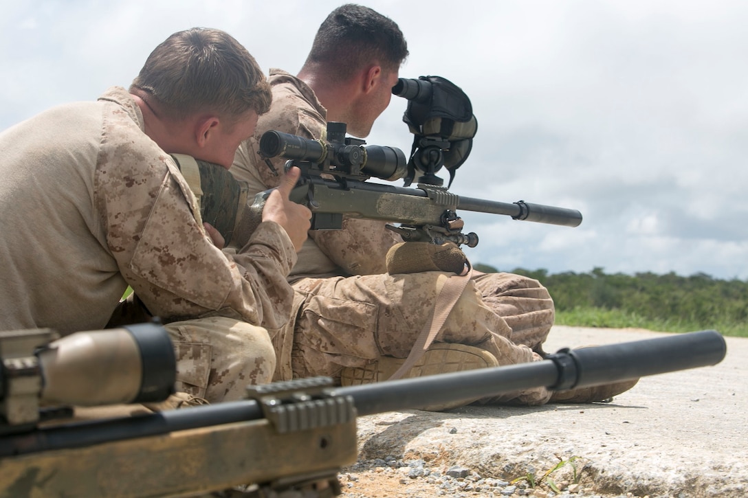 Lance Cpl. Seth M. Richardson, left, fires an M40A5 sniper rifle while Cpl. Aaron A. Gobidas spots the rounds and provides corrections Aug. 17 at the Central Training Area in Okinawa, Japan. Teamwork can mean the difference between mission accomplishment and mission failure. The M40A5 rifle is a bolt-action sniper rifle with a muzzle velocity of 2,550 feet per second and an effective firing range of up to 900 meters. Richardson is a Carbondale, Illinois, native, and Gobidas is a Cleveland, Ohio, native. Both are reconnaissance men with 3rd Reconnaissance Battalion, 3rd Marine Division, III Marine Expeditionary Force. 