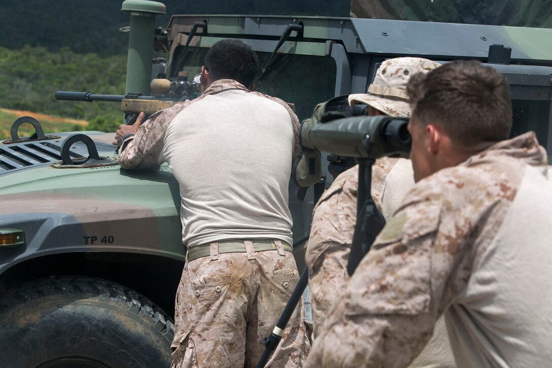 Cpl. Rafael A. Dehoyos, left, a San Antonio, Texas, native, fires an M40A5 sniper rifle Aug. 17 at the Central Training Area in Okinawa, Japan. The Marines sometimes use natural or inanimate objects to stabilize their rifles when the prone position is not an option. The M40A5 rifle is a bolt-action sniper rifle with a muzzle velocity of 2,550 feet per second and an effective firing range of up to 900 meters. Dehoyos is a reconnaissance man with 3rd Reconnaissance Battalion, 3rd Marine Division, III Marine Expeditionary Force. 
