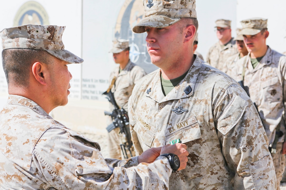 Brigadier Gen. Daniel D. Yoo, left, commander, Regional Command (Southwest) and Marine Expeditionary Brigade – Afghanistan, pins the Navy and Marine Corps Commendation Medal with Combat Distinguishing Device onto Petty Officer 2nd Class Joshua Van Horn, a corpsman with 1st Air Naval Gunfire Liaison Company, during an award ceremony aboard Camp Leatherneck, Afghanistan, Sept. 17, 2014. Van Horn received the award for heroic achievement while being a first responder to Marine casualties after their vehicle struck an improvised explosive device.