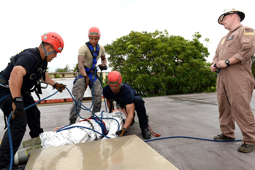 Master Sgt. Jason Berry, right, supervises Andersen Air Force Base and Naval Base Guam firefighters as they secure a simulated victim on the roof of a hot spot during the Defense Department Rescue Technician Course Sept. 16, 2014, on Andersen AFB, Guam. Firefighters attending the course were tasked with rescuing two stranded victims as part of their qualification to become rescue technicians. Berry is the 554th RED HORSE Squadron Fire and Emergency Services superintendent. (U.S. Air Force photo/Tech. Sgt. Zachary Wilson)