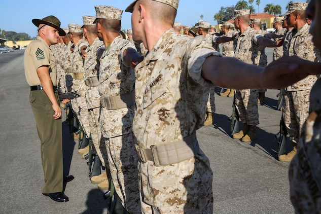 A drill instructor inspects the uniforms of recruits of Platoon 1041, Charlie Company, 1st Recruit Training Battalion, during Final Drill at Marine Corps Recruit Depot San Diego, Calif., Sept. 15. Having a well maintained uniform was part of the evaluation during Final Drill. Any discrepancies such as missing buttons and improper wearing of the uniform caused the platoon to lose points in their evaluation. 