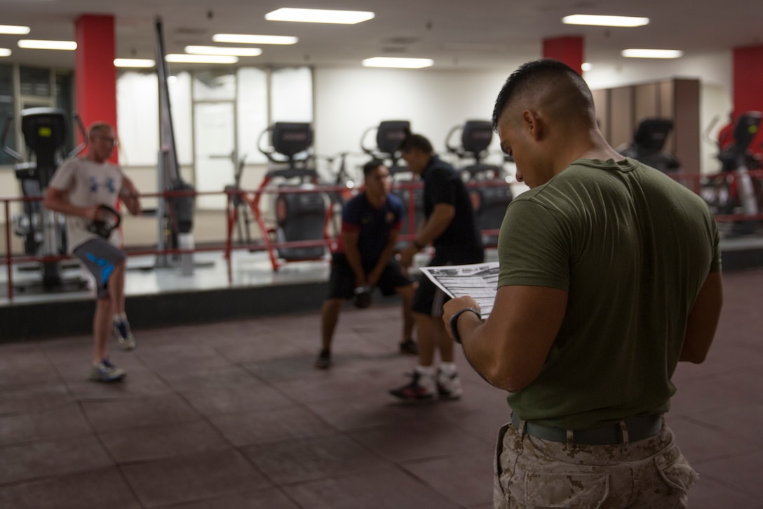 Cpl. Jonathan Soriano, a level-one High Intensity Tactical Training instructor with Marine Aviation Logistics Squadron (MALS) 11, looks over a list of exercises during a morning workout with his Marines at the HITT Center aboard Marine Corps Air Station Miramar, Calif., Sept. 17. Soriano put his education on hold while he transitions out of the Marine Corps, but continues to help friends and peers work out and studies fitness, his passion, through articles and books.