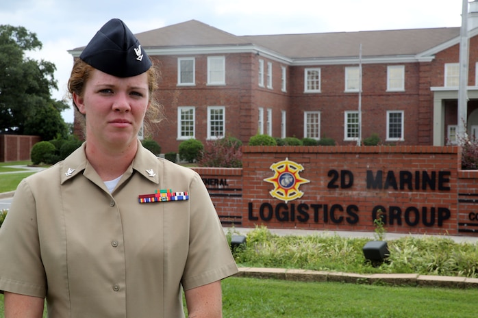 Petty Officer 3rd Class Elizabeth J. Miller, a corpsman with Combat Logistics Regiment 25 and native of Boaz, Alabama, poses for a picture in front of the 2nd Marine Logistics Group building. September 19, 2014. Larry T. Flesher, an electrical technician and native of Valdosta, Georgia crashed his car into oncoming traffic the morning of September 12, 2014 while crossing the Sneads Ferry Bridge on his way to work on Camp Lejeune. With the help of two Marines, Miller was able to pull Flesher from his car and perform first aid until the arrival of emergency medical services. Flesher lived thanks to Miller's quick thinking and composure under pressure. Flesher expressed his deep gratitude to Miller when they were reunited, calling her an angel.