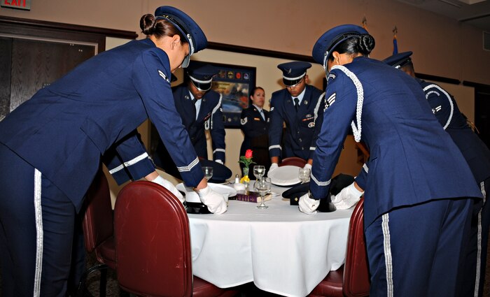 The Beale Air Force Base Honor Guard places the service covers of each military branch upon a table representing lost or missing service members during a POW/MIA remembrance breakfast Sept. 19, 2014. National POW/MIA Recognition Day is observed across the nation on the third Friday of September each year to remember prisoners of war and those missing in action, as well as their families. (U.S. Air Force photo by Airman 1st Class Ramon A. Adelan/Released)