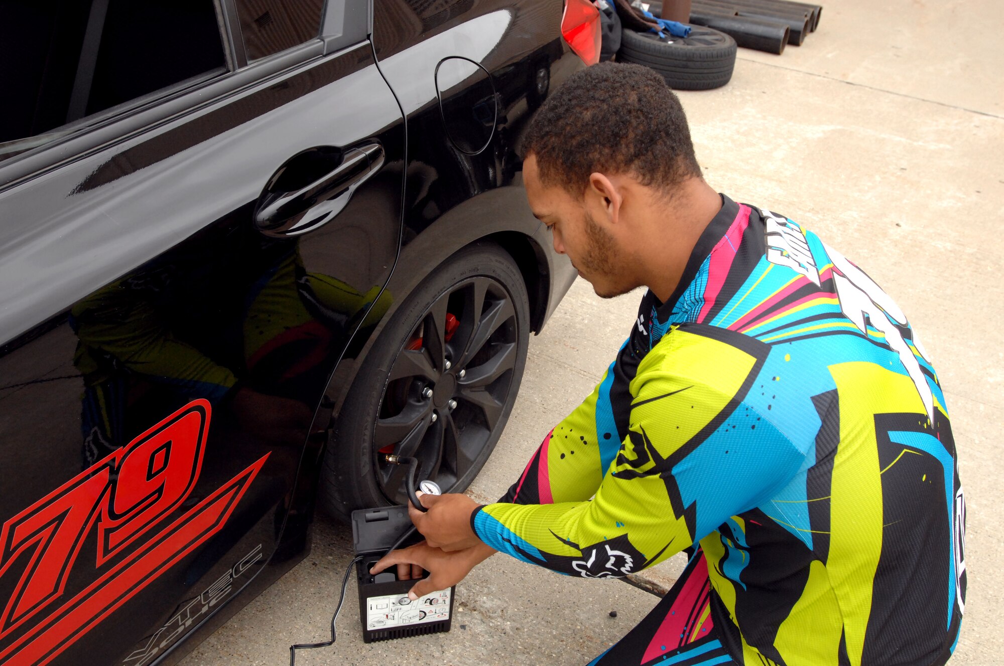 Tallon Early, a plumber from Fargo, N.D., checks the tire pressure on his 2012 Honda Civic Si before the Autocross event held Sept. 14, 2014, at the free zone in front of the 3-Bay Hangar on Grand Forks Air Force Base, N.D. Nearly 60 entrants driving cars of every make and model participated in the day-long event, with proceeds going to benefit the Wounded Warrior Project. (U.S. Air Force photo/Staff Sgt. Susan L. Davis)