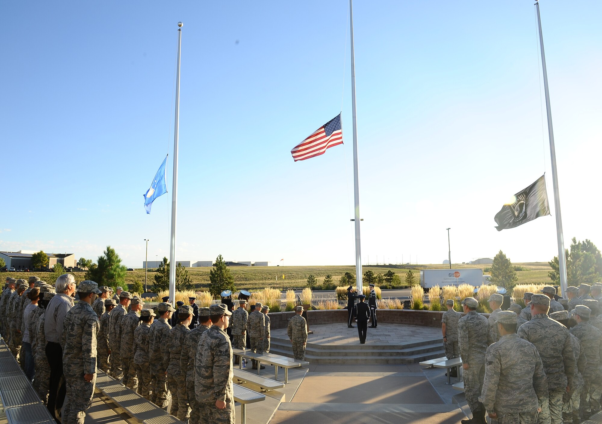 Team Buckley members watch as the American flag, Air Force flag and POW/MIA flags are secured by the Mile High Honor Guard during the National POW/MIA Recognition Day ceremony Sept. 19, 2014, at the 460th Space Wing headquarters building on Buckley Air Force Base, Colo. The observance was held in honor of those who suffered as prisoners of war or are missing in action. (U.S. Air Force photo by Tech. Sgt. Rob Hazelett/Released)