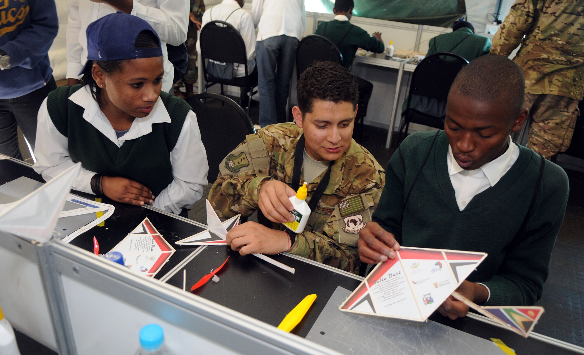 Airman 1st Class Eduardo Acosta builds model airplanes with South African students Sept. 19, 2014, as part of the Youth Development Program at the Africa Aerospace & Defence Expo 2014 Sept. 17, 2014, at Waterkloof Air Force Base, Pretoria, South Africa. U.S. Air Force Airmen and U.S. Army Soldiers, including the United States Air Forces in Europe band and Golden Knights parachute demonstration team, attended the 8th annual multinational event. United States military aircraft, including a C-130J Super Hercules and C-17 were on static display at the show. (U.S. Air Force photo by Tech. Sgt. Austin M. May/Released)