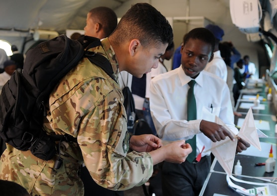 Senior Airman Jaime Molina builds model airplanes with South African students Sept. 19, 2014, as part of the Youth Development Program at the Africa Aerospace & Defence Expo 2014 Sept. 17, 2014, at Waterkloof Air Force Base, Pretoria, South Africa. U.S. Air Force Airmen and U.S. Army Soldiers, including the United States Air Forces in Europe band and Golden Knights parachute demonstration team, attended the 8th annual multinational event. United States military aircraft, including a C-130J Super Hercules and C-17 were on static display at the show. (U.S. Air Force photo by Tech. Sgt. Austin M. May/Released)