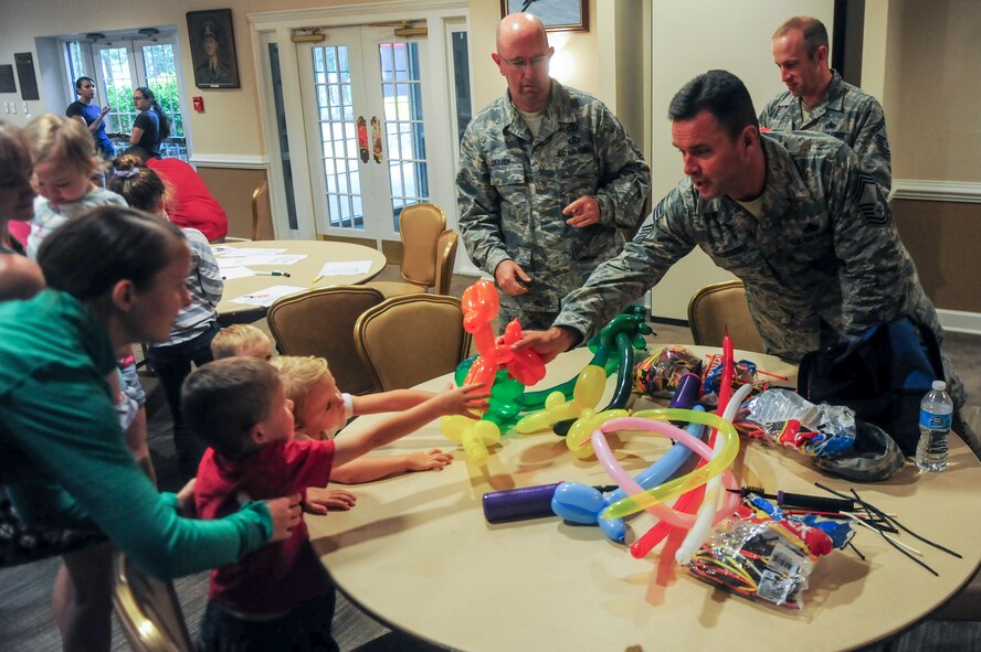 Chief Master Sgt. Bradley Truesdell, 4th Maintenance Group superintendent, hands a balloon animal to a child during the “Hearts Apart” event Sept. 17, 2014, at Seymour Johnson Air Force Base, North Carolina.The event focused on relieving the pressures families sustain when a member is deployed and served as a venue to ensure families are connected with the wing’s many helping agencies and resources. (U.S. Air Force photo/Airman 1st Class Brittain Crolley) 

