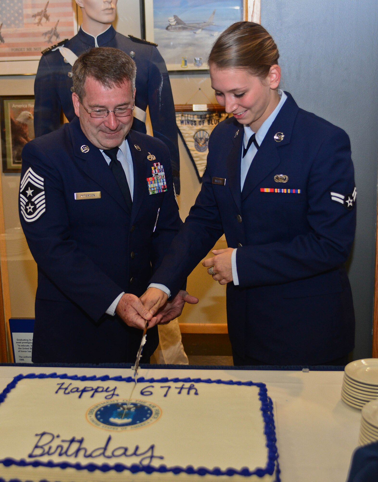 Chief Master Sgt. Kevin Peterson, 28th Bomb Wing command chief, and Airman 1st Class Rebecca Imwalle, 28th BW public affairs photojournalist, cut a birthday cake in honor of the Air Force’s 67th birthday during the Civic Leader Social held in the South Dakota Air and Space Museum in Box Elder, S.D., Sept. 18, 2014. The event recognized incoming and outgoing honorary commanders while celebrating the Air Force’s 67th birthday. (U.S. Air Force photo by Senior Airman Zachary Hada/Released)