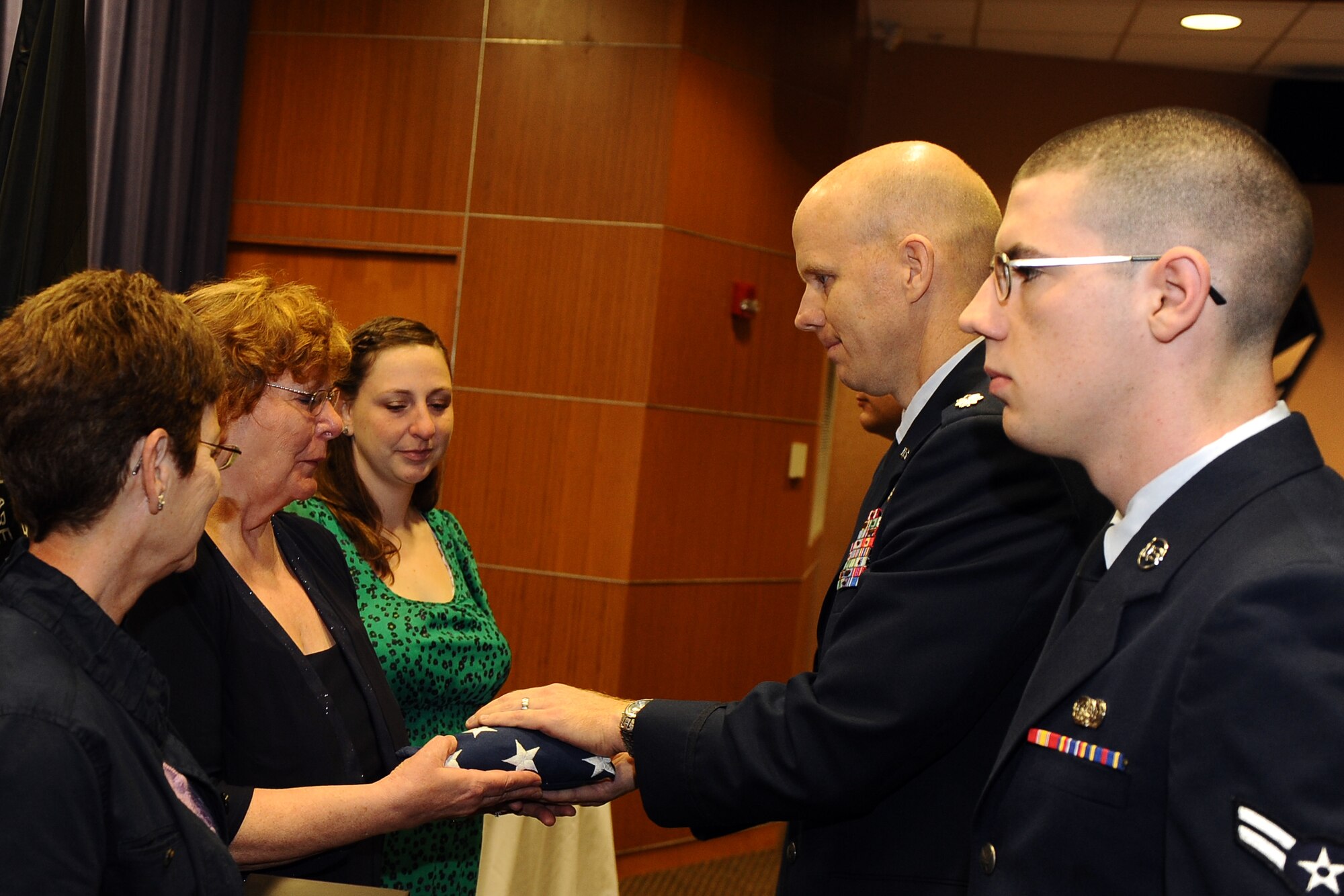 Family members of U.S. Air Force Senior Master Sgt. Thomas Smith, a WWII prisoner of war, receive an American flag during the Air Force Weather Agency Prisoner of War/Missing in Action ceremony Sept. 19 in the AFWA auditorioum. Smith, a weather observer and forecaster, was forced to parachute from a B-17 bomber in 1947, minutes before it exploded. (U.S. Air Force photo by Josh Plueger)