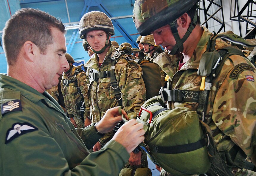 Sgt. Gareth Saunders, Royal Air Force personal jumping instructor, conducts a final equipment check on members of II Squadron onboard a RAF 47 Squadron C-130J Hercules before a combat equipment jump Sept. 11 at RAF Brize Norton, England. This jump served as the finale of Exercise Global Eagle. (Royal Air Force courtesy photo by Cpl. Barbara Robinson/Released)