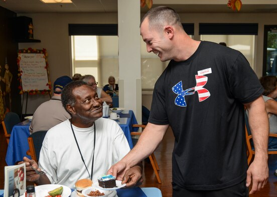 Tech. Sgt. Horace Marceau, 412th Maintenance Squadron, offers a piece of birthday cake to resident, Larry Baker, who served in the United States Army. (U.S. Air Force photo by Rebecca Amber)