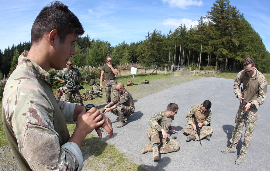 Lance Cpl. Jason Acid, Royal Air Force Regiment, keeps track of the time as a team of force protection specialists assemble and disassemble foreign weapons during the military skills phase of Exercise Global Eagle Sept. 8 at Sennybridge Training Area, Wales. This course tests force protection specialists' proficiency at successfully handling the unfamiliar, foreign weapons they may encounter on real-world missions. (Royal Air Force courtesy photo by Cpl. Barbara Robinson/Released)