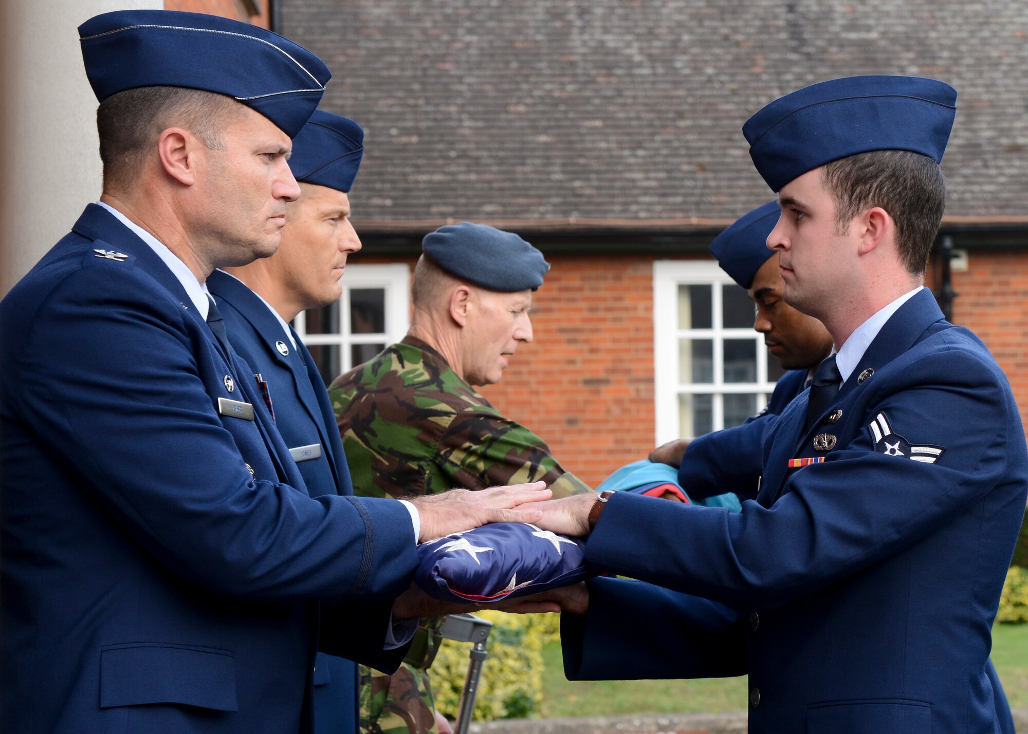 U.S. Air Force Col. Kenneth T. Bibb Jr., left, 100th Air Refueling Wing commander, receives the U.S. flag from a flag detail after a retreat ceremony Sept. 19, 2014, on RAF Mildenhall, England. RAF Mildenhall held a ceremonial retreat in honor of the service members held as prisoners of war or missing in action. Retreat is a long-standing tradition honoring the flag and signaling the end of the duty day. (U.S. Air Force photo/Senior Airman Victoria H. Taylor/Released)