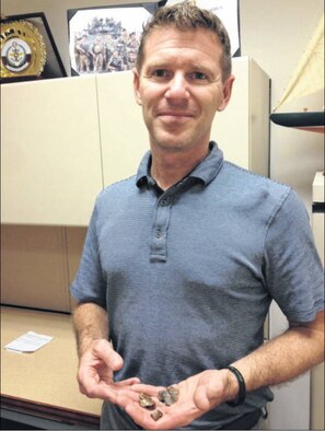Timothy O'Sullivan, who now serves as an instructor and class manager of the Security Cooperation Action Officer Course at the Defense Institute of security Assistance management, Wright-Patterson Air Force Base, holds pieces of shrapnel, sent to him by British comrades as "souvenirs" of the weapon that seriously injuried him. (photo by Amy Rollins)