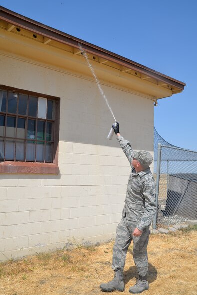 Airman 1st Class Brandon Burkholder, 60th Civil Engineer Squadron Pest Management technician, sprays wasp colonies located at the Bird Aircraft Strike Hazard Building on Travis Sept. 10. The pest management team is tasked with handling and eliminating insects, along with rodents and small animals, for populated areas on the installation. (U.S. Air Force photo/Senior Airman Bryan Swink)