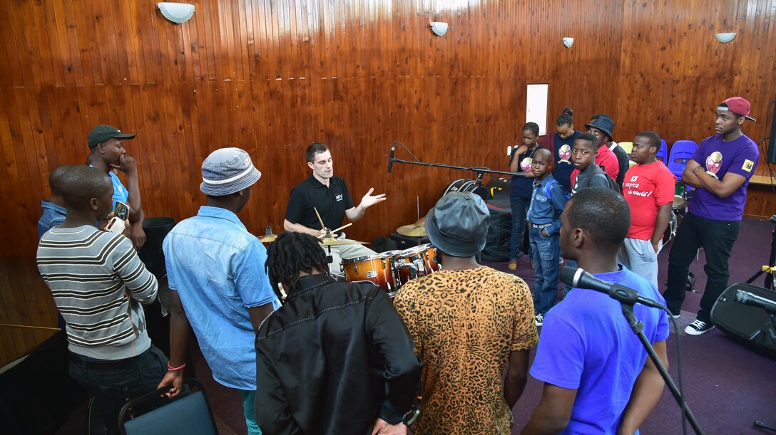 Senior Airman Edward Zaryky, U.S. Air Forces in Europe jazz band, Wings of Dixie drummer, (center) teaches and explains techniques for drumming to South African music students prior to a free, live concert at the Music Academy of Gauteng in Benoni, South Africa, Sept 18, 2014. Zaryzy and the five other members of Wings of Dixie played a two-hour musical set featuring the musical styles of jazz, funk and blues. (U.S. Air Force photo/Staff Sgt. Travis Edwards-Released)
