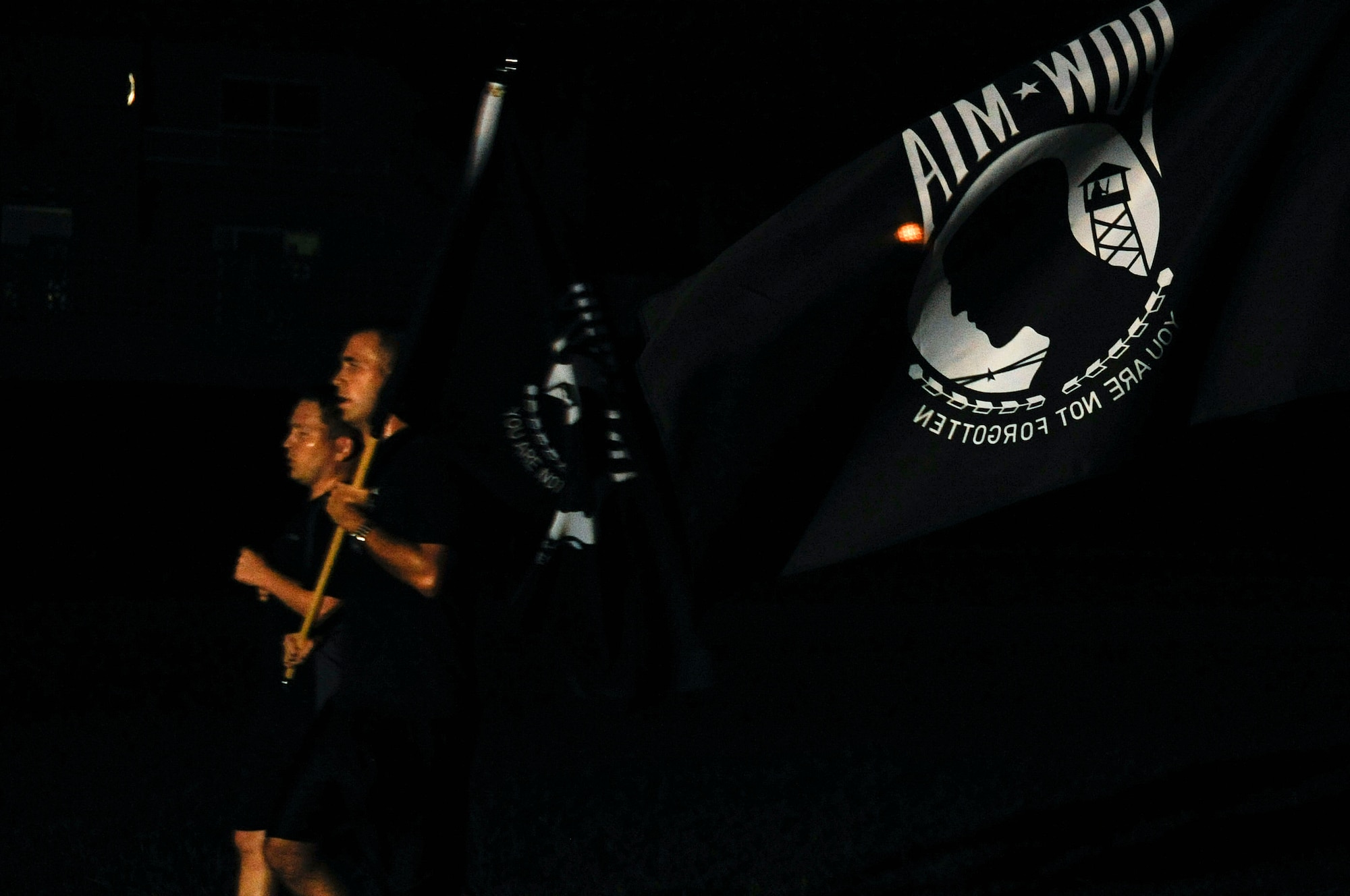 Members from the 82nd Reconnaissance Squadron run past a Prisoners of War and Missing in Action flag during the night portion of the POW/MIA 24-hour Vigil Run at Marek Park on Kadena Air Base, Japan, Sept. 19, 2014. Various groups and squadrons from Team Kadena signed up for a designated time slot to run during the event. (U.S. Air Force Photo by Staff Sgt. Darnell T. Cannady/Released) 
